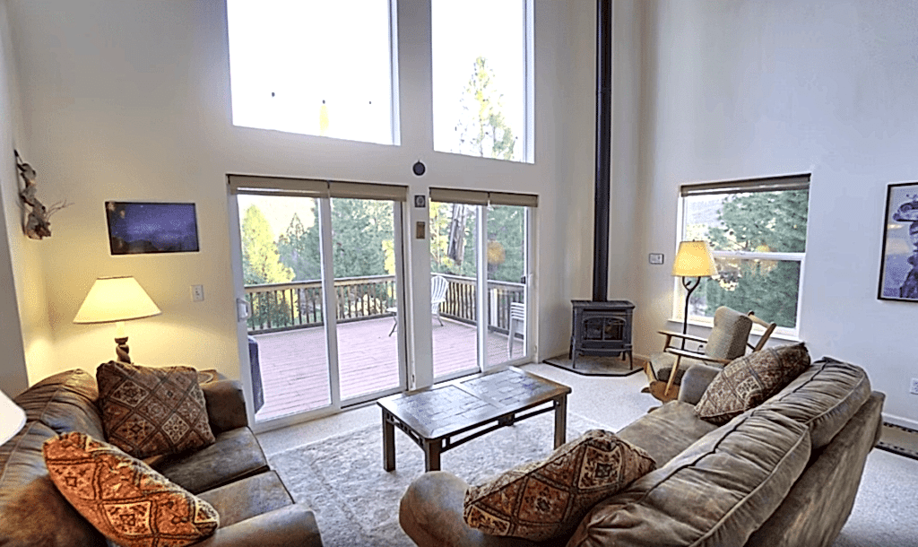 living room with tall windows and wood stove